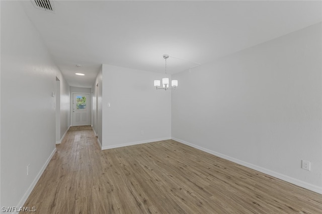 unfurnished room featuring light hardwood / wood-style floors and a notable chandelier