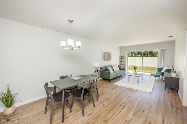 dining space with light hardwood / wood-style floors and an inviting chandelier