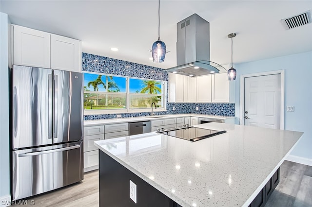 kitchen with stainless steel appliances, light hardwood / wood-style floors, white cabinets, hanging light fixtures, and island exhaust hood