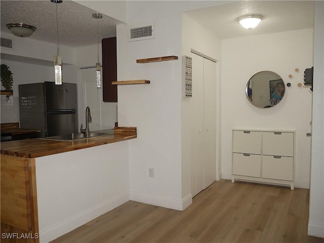 kitchen featuring a sink, open shelves, baseboards, freestanding refrigerator, and wood finished floors