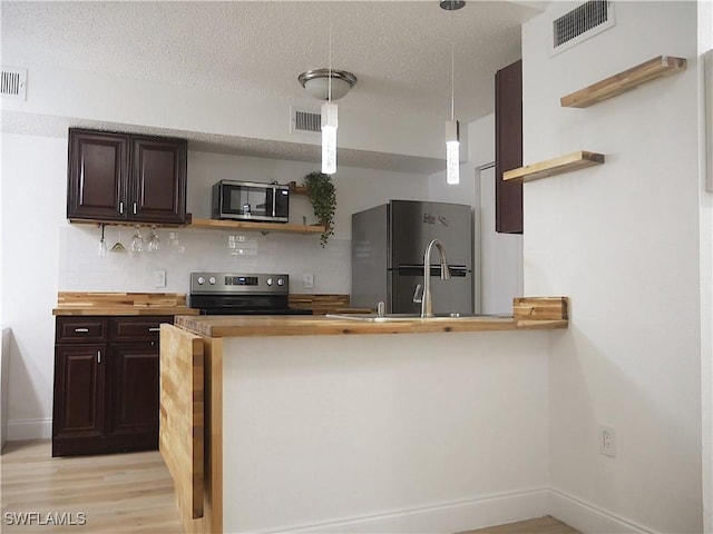 kitchen featuring appliances with stainless steel finishes, visible vents, open shelves, and dark brown cabinetry