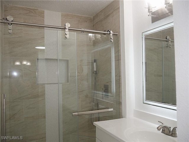 full bath with a textured ceiling, vanity, and a shower stall