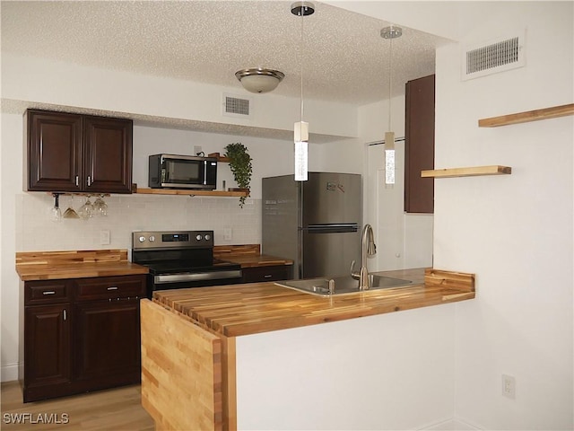 kitchen with open shelves, a sink, visible vents, stainless steel appliances, and butcher block countertops