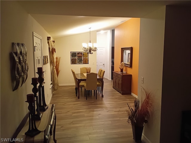 dining room featuring hardwood / wood-style flooring, a notable chandelier, and vaulted ceiling