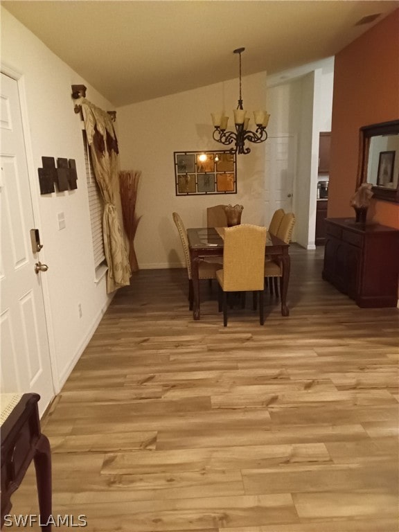 dining room with lofted ceiling, a chandelier, and light hardwood / wood-style flooring