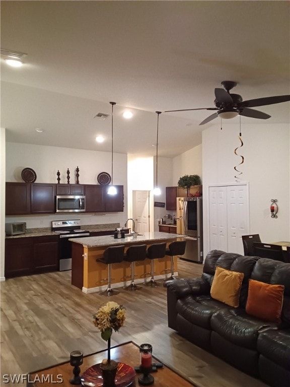 living room featuring hardwood / wood-style floors, ceiling fan, and sink