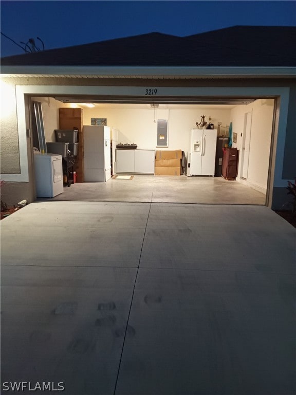 garage at twilight featuring washer / dryer and white refrigerator with ice dispenser