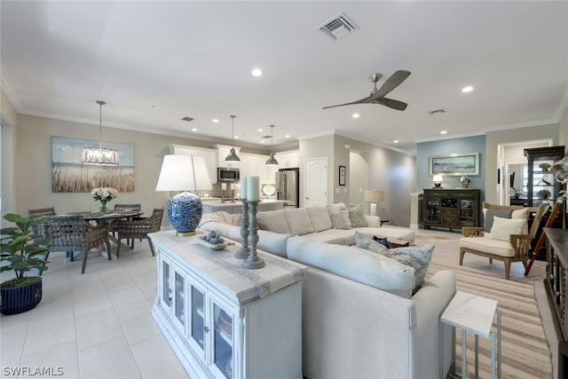 tiled living room with ceiling fan with notable chandelier and ornamental molding