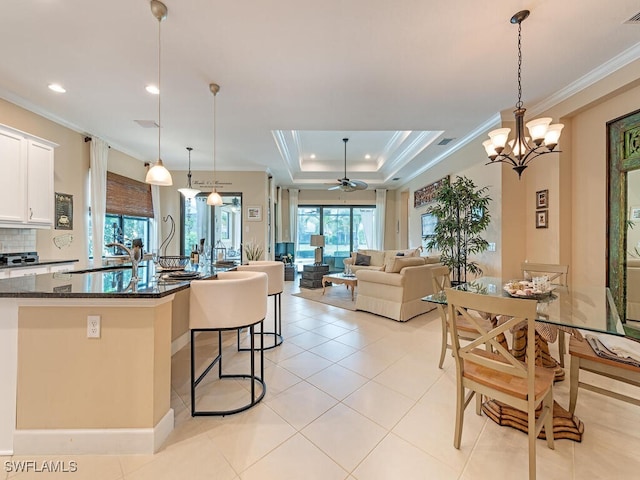 kitchen featuring dark stone countertops, ceiling fan with notable chandelier, crown molding, white cabinetry, and sink