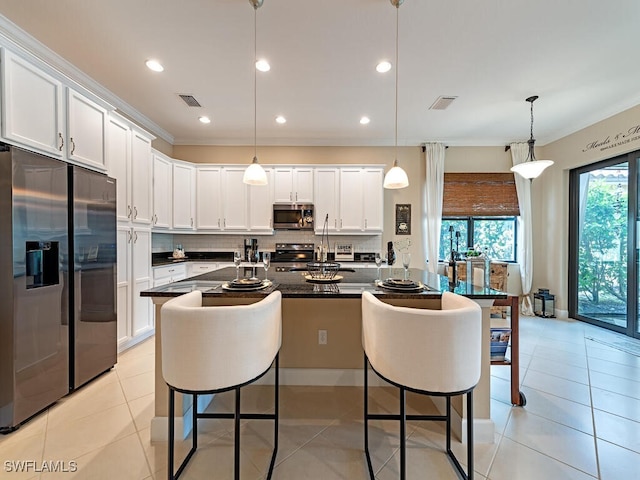 kitchen with pendant lighting, stainless steel appliances, light tile patterned floors, and white cabinetry