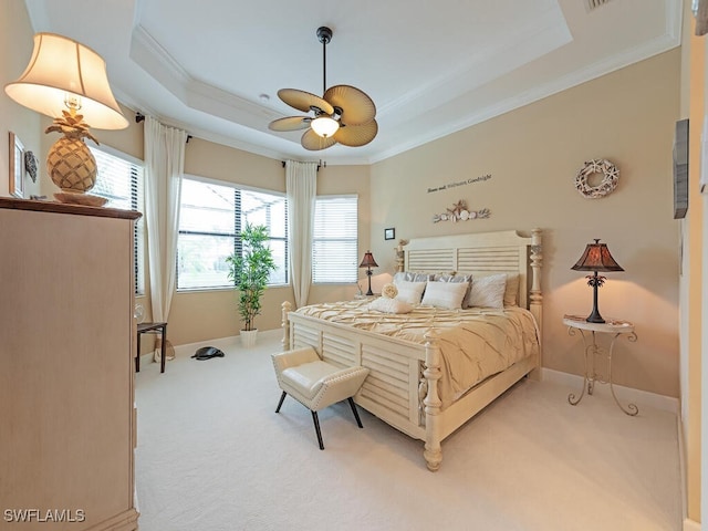 carpeted bedroom with ceiling fan, ornamental molding, and a tray ceiling