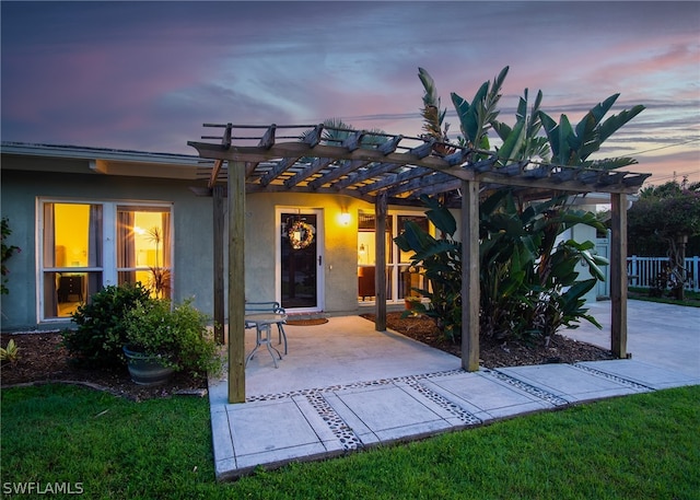 back house at dusk featuring a lawn, a pergola, and a patio area