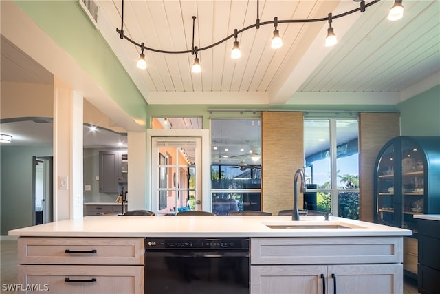 kitchen with light brown cabinetry, sink, black dishwasher, beam ceiling, and decorative light fixtures