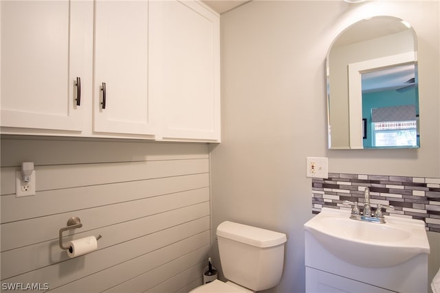 bathroom with toilet, vanity, and tasteful backsplash