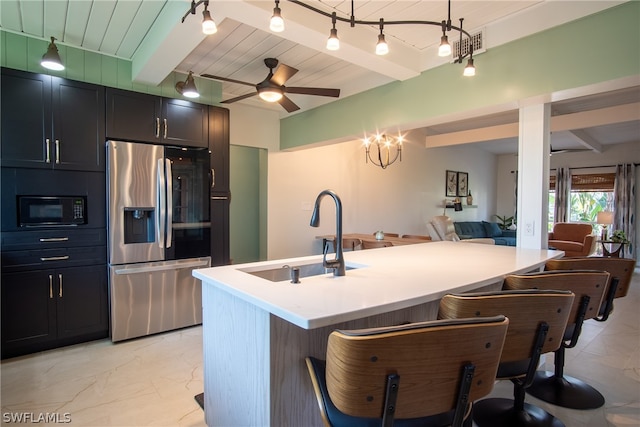 kitchen featuring ceiling fan with notable chandelier, stainless steel fridge, a breakfast bar area, and beamed ceiling