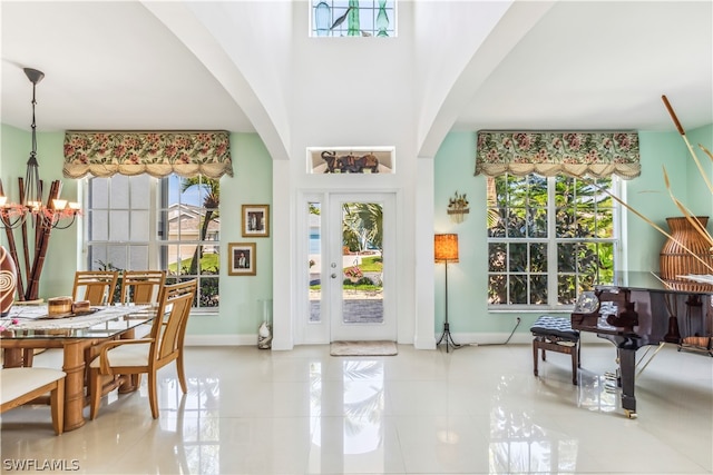 interior space with plenty of natural light, a chandelier, and a towering ceiling