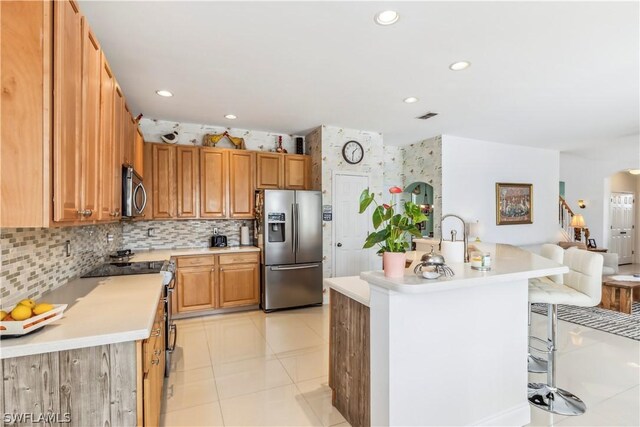 kitchen with tasteful backsplash, a breakfast bar area, an island with sink, and appliances with stainless steel finishes