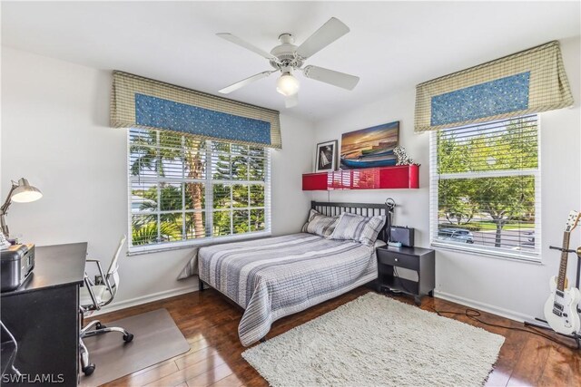 bedroom featuring multiple windows, dark wood-type flooring, and ceiling fan