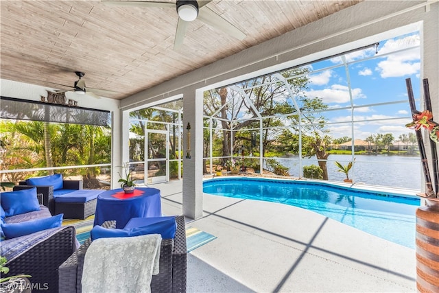 view of pool featuring outdoor lounge area, ceiling fan, glass enclosure, a patio, and a water view