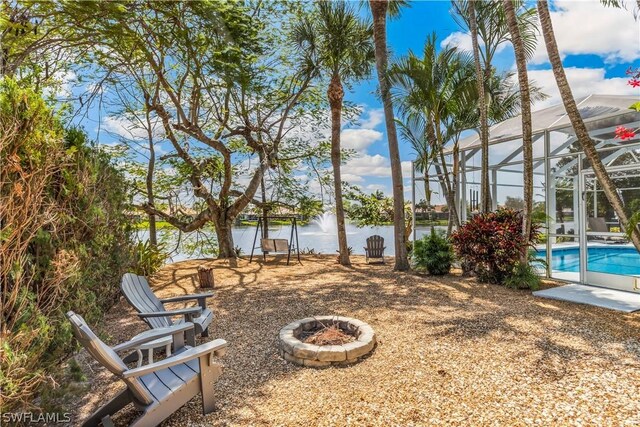 view of yard with a fire pit, a water view, and glass enclosure