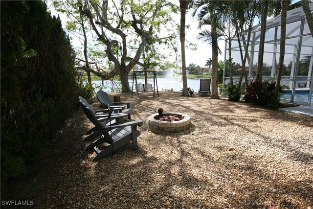 view of yard featuring a lanai, a water view, and a fire pit