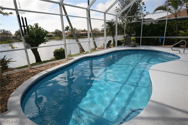 view of pool with a patio area, glass enclosure, and a water view