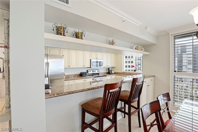 kitchen featuring a kitchen bar, light stone countertops, appliances with stainless steel finishes, and crown molding