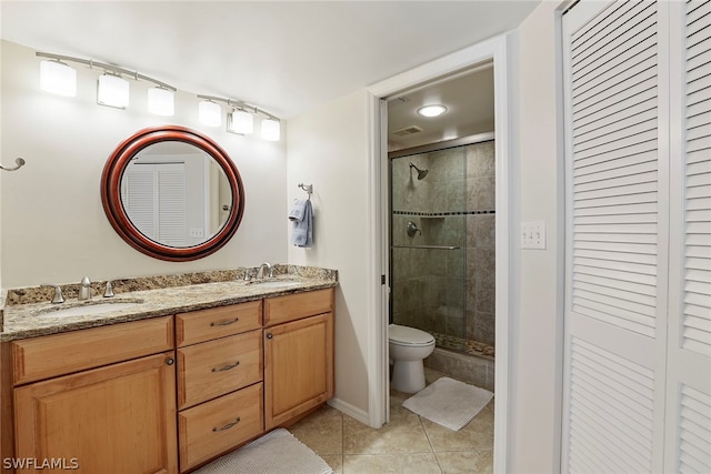 bathroom featuring double sink vanity, tile floors, a shower with door, and toilet