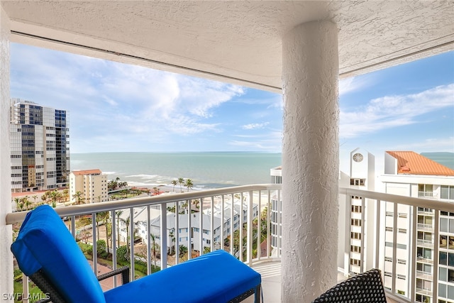 balcony with a water view and a view of the beach