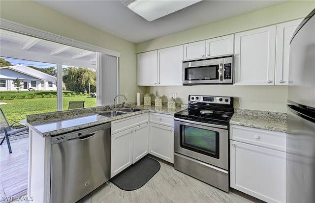 kitchen featuring light stone countertops, white cabinetry, sink, stainless steel appliances, and light tile floors