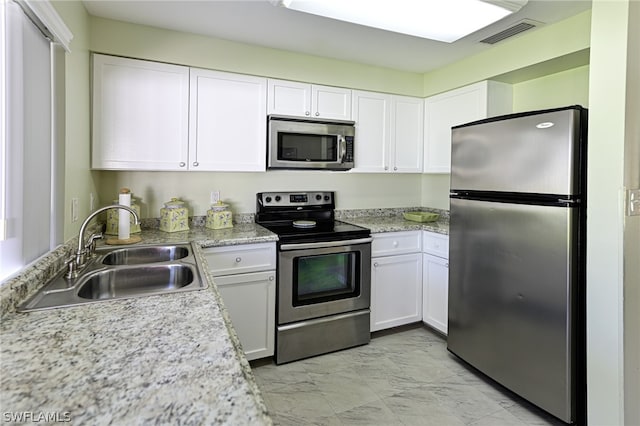 kitchen featuring appliances with stainless steel finishes, white cabinetry, sink, and light tile flooring