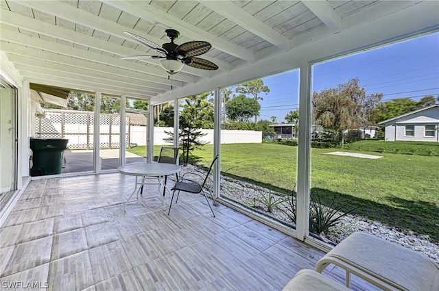 unfurnished sunroom featuring wood ceiling, ceiling fan, and beamed ceiling