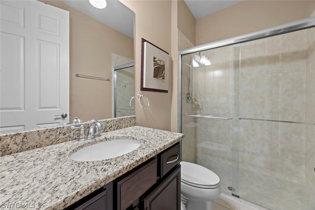 bathroom featuring toilet, large vanity, and a shower with door