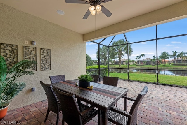 sunroom / solarium featuring a water view and ceiling fan