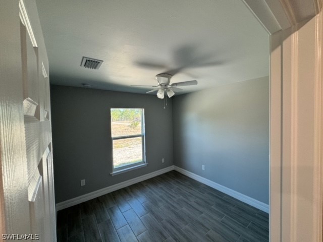 spare room featuring ceiling fan and dark wood-type flooring