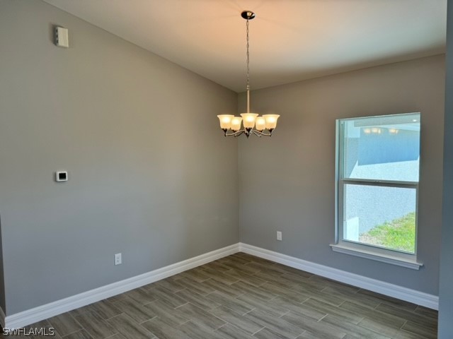 spare room featuring hardwood / wood-style floors and a chandelier