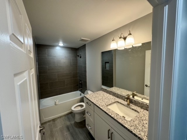 full bathroom featuring tiled shower / bath, hardwood / wood-style floors, toilet, and vanity