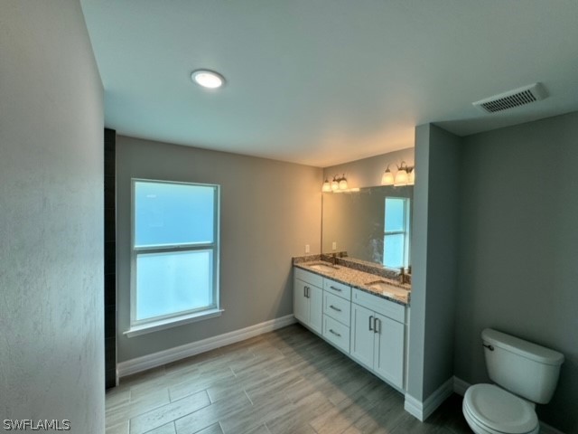 bathroom with double vanity and toilet