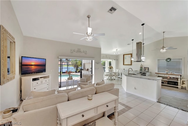 living room with ceiling fan, sink, light tile patterned floors, and lofted ceiling