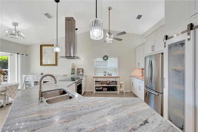 kitchen with sink, wall chimney exhaust hood, a barn door, white cabinets, and appliances with stainless steel finishes