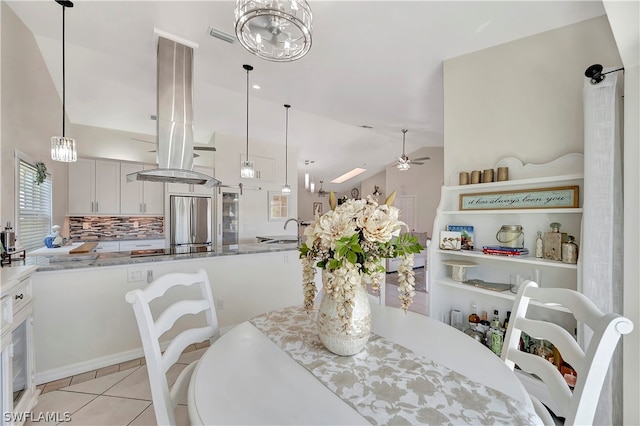 dining space with ceiling fan, lofted ceiling, sink, and light tile patterned floors