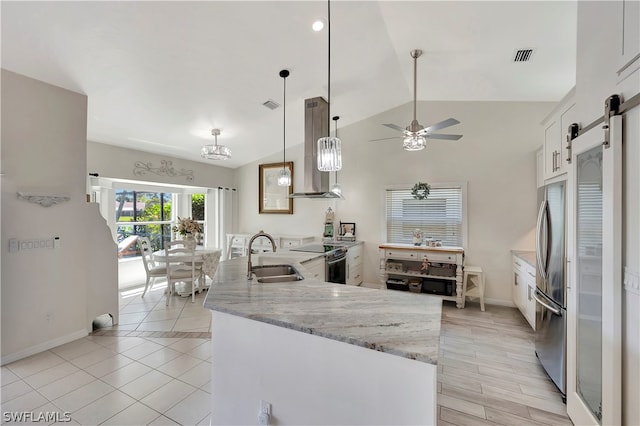 kitchen featuring white cabinets, sink, hanging light fixtures, a barn door, and extractor fan