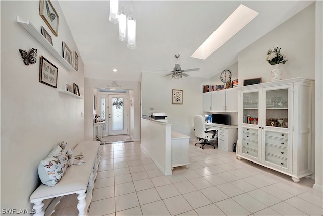 entryway with ceiling fan, light tile patterned flooring, and lofted ceiling with skylight