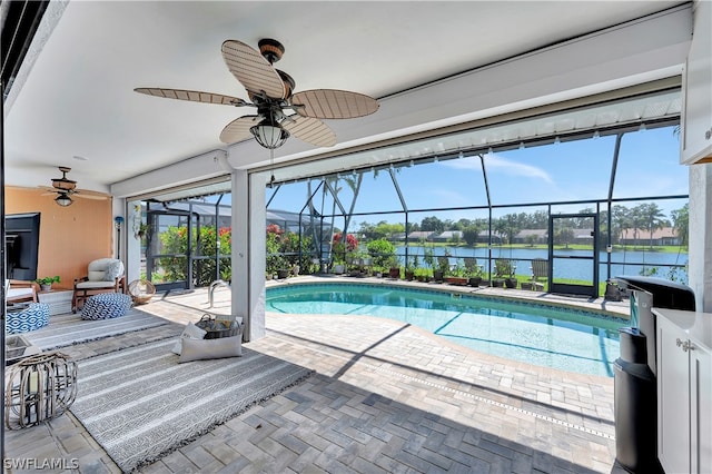 view of swimming pool featuring glass enclosure, ceiling fan, a patio area, and a water view