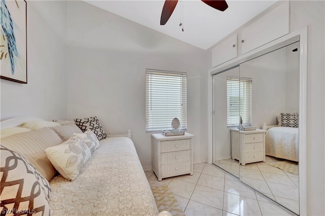 bedroom with ceiling fan, light tile patterned flooring, lofted ceiling, and a closet