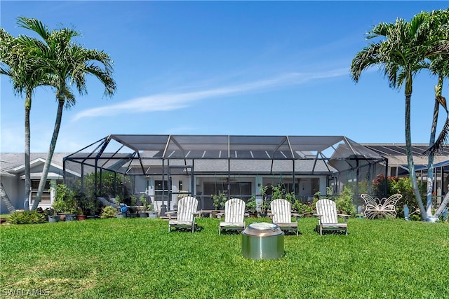 rear view of house featuring a lawn and glass enclosure