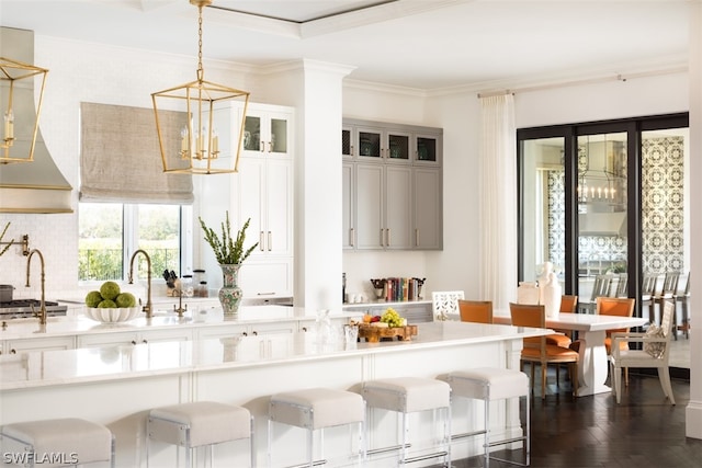 kitchen with crown molding, a breakfast bar area, pendant lighting, and white cabinets