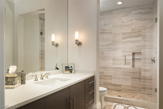 bathroom with vanity, toilet, and a tile shower