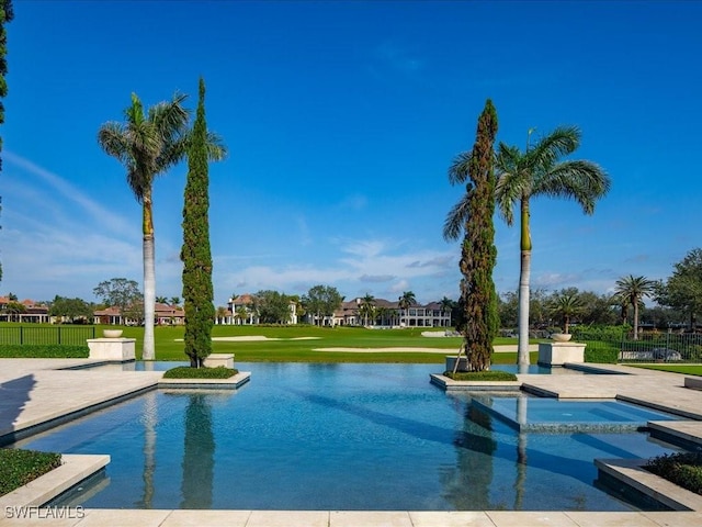 view of pool with a patio area, a lawn, a water view, and an in ground hot tub