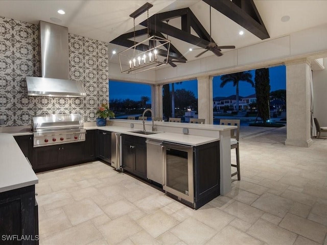 kitchen featuring pendant lighting, sink, a kitchen bar, kitchen peninsula, and wall chimney range hood